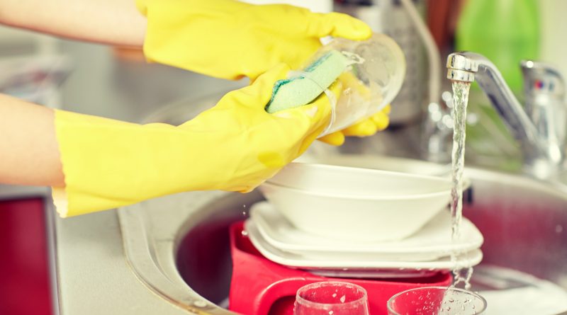 people, housework, washing-up and housekeeping concept - close up of woman hands in protective gloves washing dishes with sponge at home kitchen