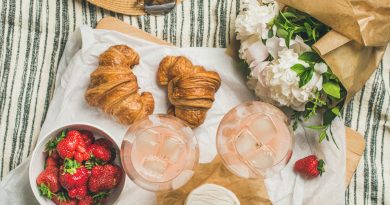 Flat-lay of rose wine, strawberries, croissants, brie cheese, flowers