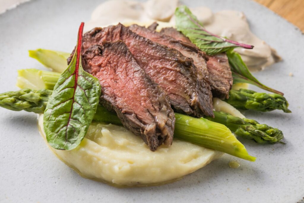 Hovädzí steak so zemiakovým pyré, špargľou a hubovou omáčkou.