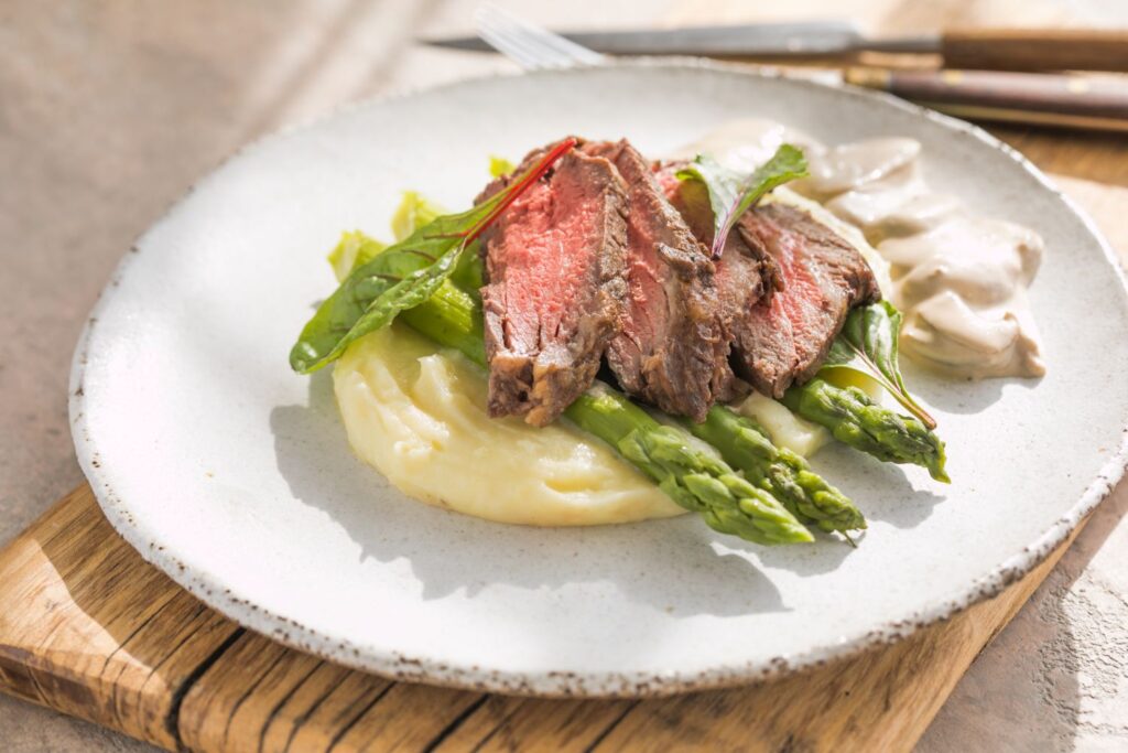 Hovädzí steak so zemiakovým pyré, špargľou a hubovou omáčkou.